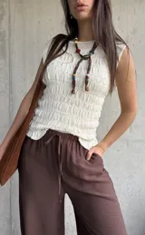 Blusa de punto sin mangas en color natural, con textura fruncida en todo el diseño y cuello redondo.