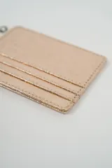 Tarjetero minimalista de color dorado metálico, con múltiples ranuras para tarjetas.