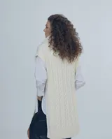 Chaleco largo de punto trenzado color gris con cuello alto y cierre frontal con cremallera metálica.