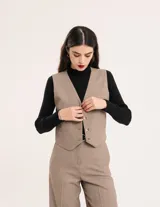 Chaleco de vestir gris oscuro con textura tipo tweed, escote en V y botones frontales. Corte levemente entallado y largo a la cintura.