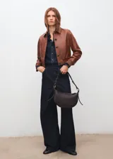 Bolso de hombro de diseño ovalado y tamaño mediano, con cierre de cremallera y asa ajustable. Cuenta con forro interior.