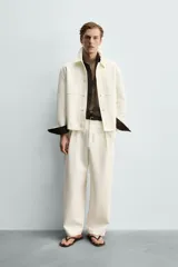 Sobrecamisa marrón de corte boxy fit en tejido compacto, con cuello solapa, manga larga con puños abotonados, bolsillos frontales de parche y cierre central de botones.