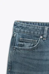 Jeans celeste de tiro alto, corte recto y largo, con cinco bolsillos y cierre frontal con cremallera y botón.