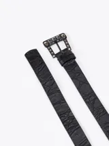 Cinturón de cuero vacuno con textura tipo croco, en color negro. Presenta una hebilla metálica rectangular decorada con pequeñas piedras oscuras.