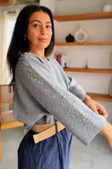 Sweater gris melange con detalles de perlas y strass aplicados en las mangas, de corte holgado y mangas largas.