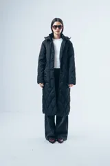 Campera acolchada de largo midi en color negro, con diseño de matelassé romboidal, cierre frontal con botones y capucha desmontable.