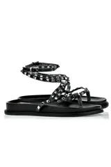 Sandalias planas negras con tiras finas y tobillera ajustable, adornadas con tachas plateadas.