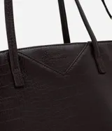 Cartera tipo shopper de gran tamaño, confeccionada en poliuretano con textura efecto crocco. Presenta doble asa fija para llevar al hombro y una correa larga desmontable con herrajes dorados. Cuenta con cierre superior por cremallera.