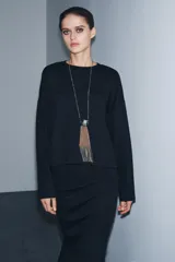Falda midi de tiro medio confeccionada en tejido soft, con cintura elástica y abertura en la parte posterior.