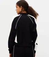 Campera deportiva de cuello alto y cierre frontal, color negro con franjas blancas en las mangas y costuras decorativas contrastantes. Cuenta con bolsillos laterales y puños ajustados.