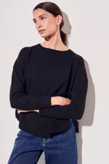 Sweater de tejido de punto en color negro, con corte oversize, cuello redondo y mangas largas con puños acanalados.