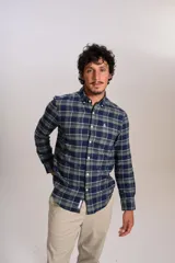 Camisa de manga larga confeccionada en tejido de franela con estampado de cuadros en tonos azul marino y verde. Presenta cuello abotonado, cierre frontal con botones y un bolsillo en el pecho con el logo bordado de la marca.