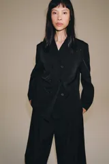 Blazer cruzado Zara de color negro, con cuello de solapa, manga larga y bolsillos laterales ocultos en la costura. Cuenta con cierre frontal de botones.