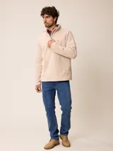 Sweater de polar color beige, con cuello alto y cierre frontal parcial. Presenta un pequeño logo bordado en el pecho.
