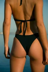 Bikini negro de lycra texturada, con corpiño triángulo invertido con breteles en lycra brillante a tono y bombacha vedetina.