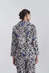 Pijama de camisa y pantalón con estampado floral en tonos azul, blanco y negro. Camisa de mangas largas con detalle de vivos a contratono en lurex plateado en el cuello y en las mangas.