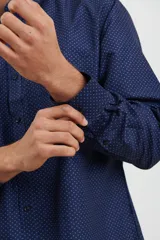 Camisa de manga larga en color azul oscuro con estampado de micro puntos claros. Presenta cuello con botones, cierre frontal abotonado y puños ajustables.