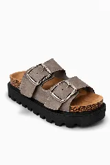 Sandalias de dos tiras anchas color gris con hebillas metálicas plateadas. Tienen una plantilla de corcho y una suela gruesa de goma negra con relieve.