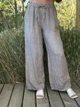 Pantalón gris de lino con corte ancho, cintura elástica con cordón y bolsillos laterales.