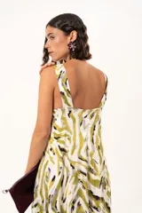 Vestido largo de tela sedosa con estampado abstracto en tonos verde oliva, blanco y negro. Presenta escote en V profundo, tirantes anchos y tajos laterales pronunciados en la falda.