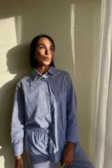 Conjunto de pijama azul a rayas blancas, compuesto por una camisa de manga larga con cuello y un pantalón largo.