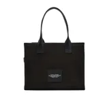 Bolso tipo tote grande de Marc Jacobs, confeccionado en lona de algodón color negro. Presenta diseño utilitario con múltiples bolsillos frontales con solapa, un bolsillo con cierre y el texto "THE TOTE BAG" impreso en contraste. Cuenta con asas superiores dobles.