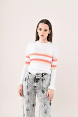 Remera de punto blanco con rayas horizontales en tonos naranja y nude en el pecho y las mangas largas. Presenta cuello redondo y puños con volados sutiles.