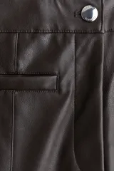 Pantalón de tiro medio en tejido revestido color marrón oscuro, con piernas acampanadas y pliegues cosidos en el frente y la espalda. Presenta cierre y botón frontal, y bolsillos insertados decorativos.