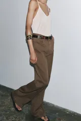 Pantalón de jean color marrón, de tiro alto, corte wide leg y relaxed fit. Cuenta con bolsillos delanteros y traseros, trabillas en la cintura, cierre frontal con cremallera, botón interior y gancho metálico.