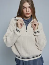 Sweater de tejido de punto grueso en color azul, con cuello alto y medio cierre frontal. Presenta detalles de rayas en contraste en los puños y el ruedo, con un diseño de corte holgado.