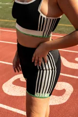 Short deportivo negro con cintura alta y rayas verticales color crema en los laterales. Presenta terminaciones con borde tejido en verde.
