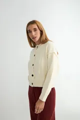Cardigan de punto color marrón chocolate, con cuello redondo, cierre frontal de botones y diseño de costuras verticales visibles. Presenta puños y ruedo acanalados.