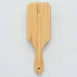 Cepillo de pelo de madera con base rectangular y púas de madera con punta redondeada.
