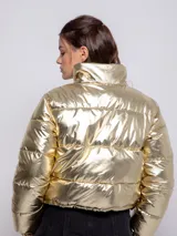 Campera puffer cropped metalizada color plateado, con cuello alto, cierre frontal, dos bolsillos laterales y elástico regulable en la cintura.
