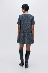 Vestido corto de tejido bouclé en tonos azul marino y blanco, con cuello redondo, manga corta y cierre frontal con botones metálicos decorativos. La falda tiene un corte acampanado con vuelo.