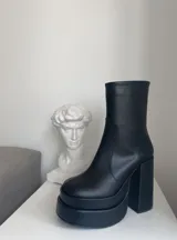 Botas negras de caña media con plataforma doble y taco cuadrado alto. Cierre lateral con cremallera.