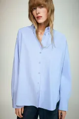 Camisa básica de corte clásico confeccionada en algodón, con cuello solapa, manga larga con puños abotonados, cierre frontal con botones y un bolsillo aplicado en el pecho.