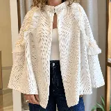 Ruana tejida de color blanco, confeccionada con lanas, con detalles de volados en gasa transparente a lo largo de los hombros y mangas, adornados con cuentas tipo perlas.