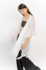Ruana abierta de tejido lurex plateado con acabado brillante, diseño ligero y terminaciones con flecos en los bordes.