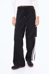 Pantalón cargo de corte amplio, color negro, con franjas laterales blancas y bolsillos tipo cargo en los costados. Presenta cintura elástica con cordón ajustable.