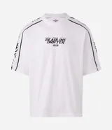 Remera de corte boxy y silueta amplia, color blanco con cuello redondo. Presenta estampa frontal con texto y gráficos tribales en las mangas.