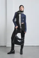 Bolso tipo hobo de cuero negro con correa ancha para el hombro.