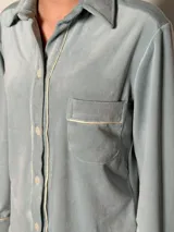 Pijama de dos piezas color rosa pálido, confeccionado en terciopelo. La camisa es de manga larga con botones frontales y bolsillo en el pecho. El pantalón es de corte recto con cintura elástica.