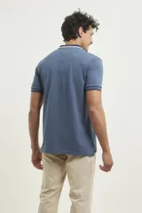 Chomba de piqué azul con cuello clásico, mangas cortas y corte recto. El cuello y los puños tienen detalles a contratono en azul marino y blanco.