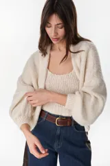 Cardigan crop de punto color crudo, con frente abierto sin botones y mangas largas abullonadas.