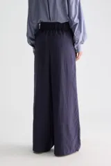 Pantalón azul marino de tiro medio con sutiles rayas verticales blancas, cintura elastizada, perneras amplias y bolsillos tipo ojal.