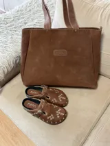 Bolso tipo tote grande confeccionado en cuero vacuno color marrón, con cierre superior, bolsillo interno y gancho para llaves.