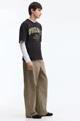 Pantalón relaxed fit en mezcla de algodón, de color beige, con cintura elástica ajustable mediante cordón, bragueta con botón y costuras decorativas giradas en las piernas.