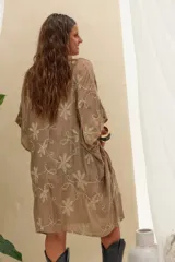 Kimono de corte amplio y mangas cortas, confeccionado en tela color caqui con delicados bordados florales en tono crudo. Cuenta con un cierre frontal con tiras largas terminadas en borlas.