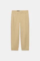 Pantalón chino de tiro medio, corte recto y holgado, con pinzas en la parte delantera. Presenta bolsillos laterales, falsos bolsillos traseros con solapa y bajo con dobladillo vuelto. Cierre frontal con cremallera y botones.